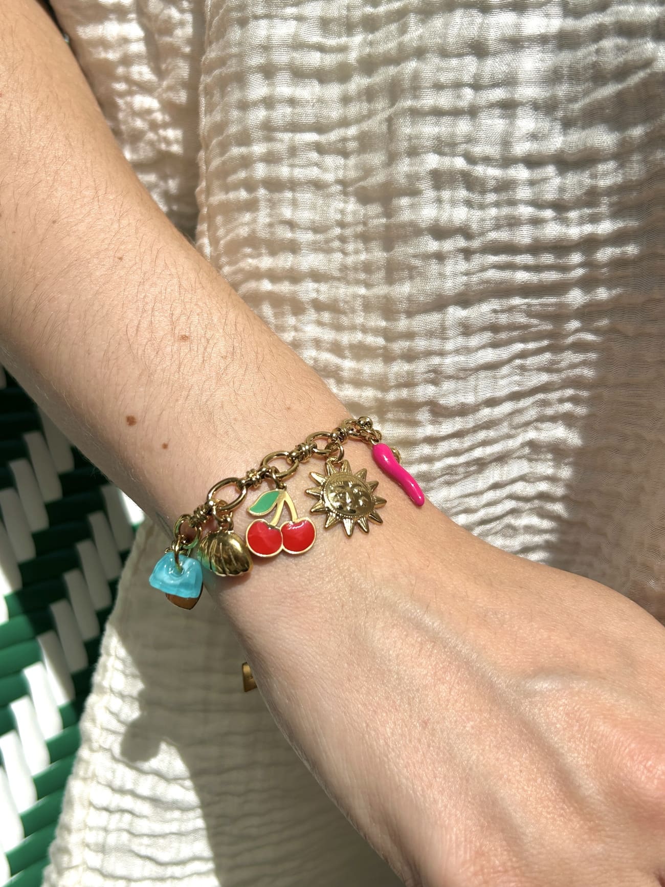 Bracelet breloque soleil et ananas porté au poignet d’une femme
