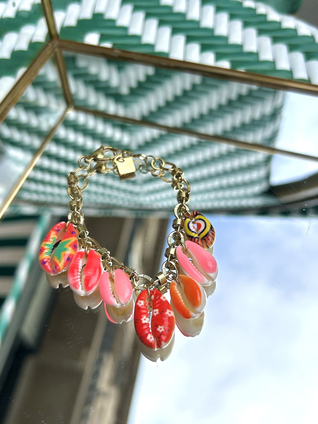 Bracelet à chaîne dorée fine avec breloque coquillage, exposé sur fond clair