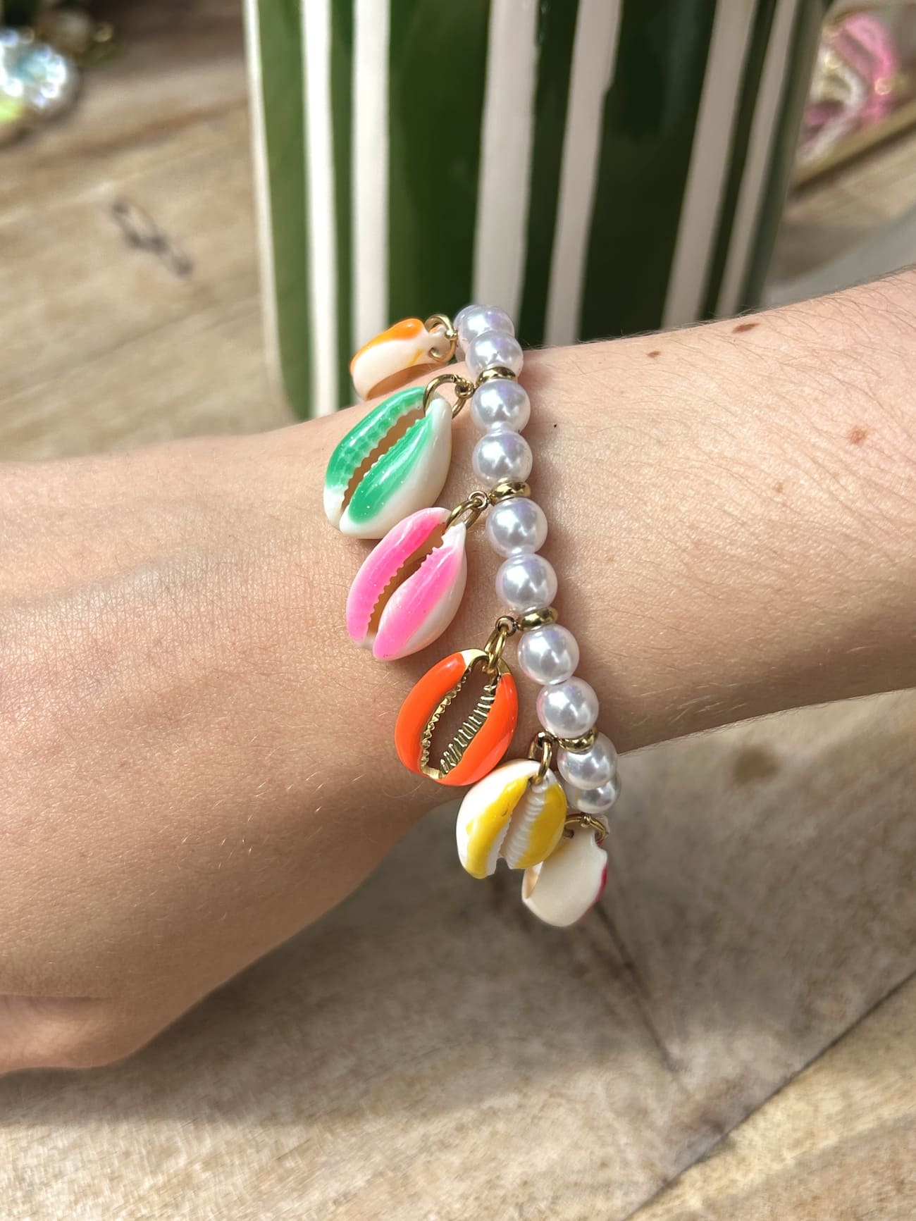 Femme portant un bracelet coquillage avec perles blanches au poignet