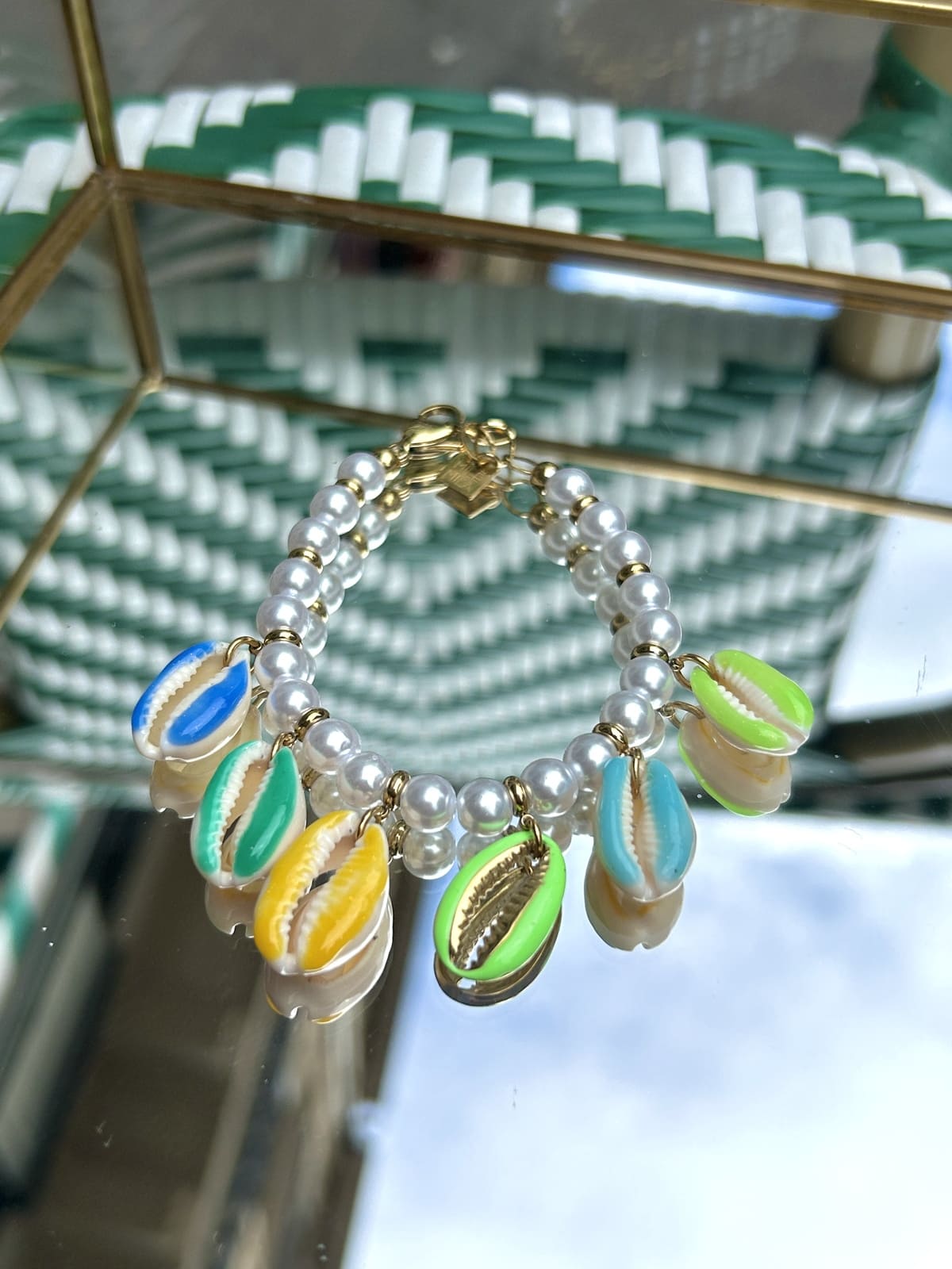 Bracelet avec coquillage oversize, perles vertes et blanches, exposé sur fond clair