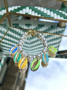 Bracelet avec coquillage oversize, perles vertes et blanches, exposé sur fond clair