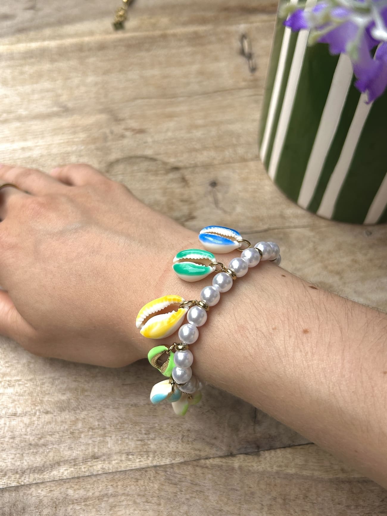 Bracelet coquillage aux perles vertes porté au poignet d’une femme