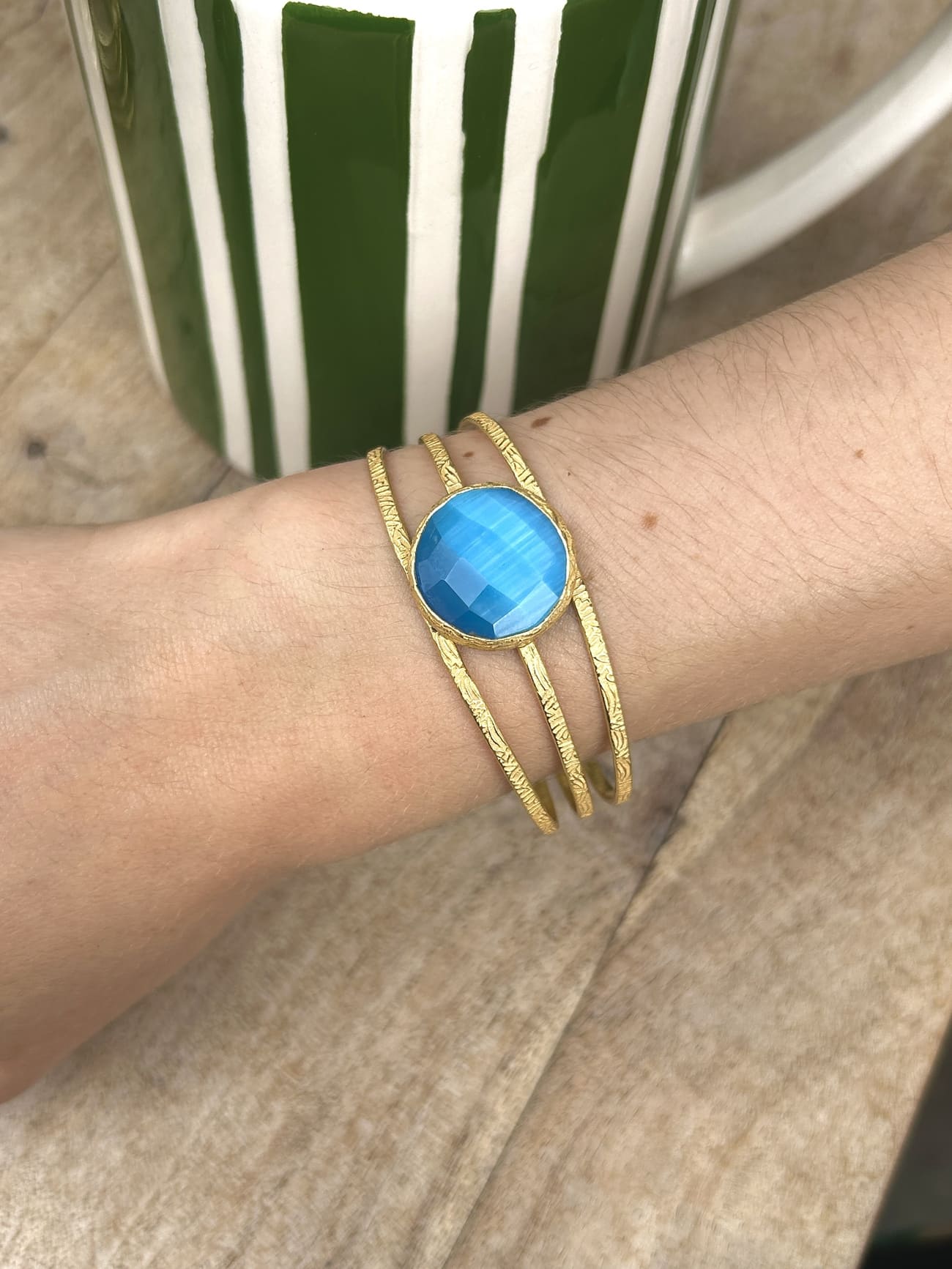 Bracelet en laiton avec pierre semi-précieuse bleue porté au poignet