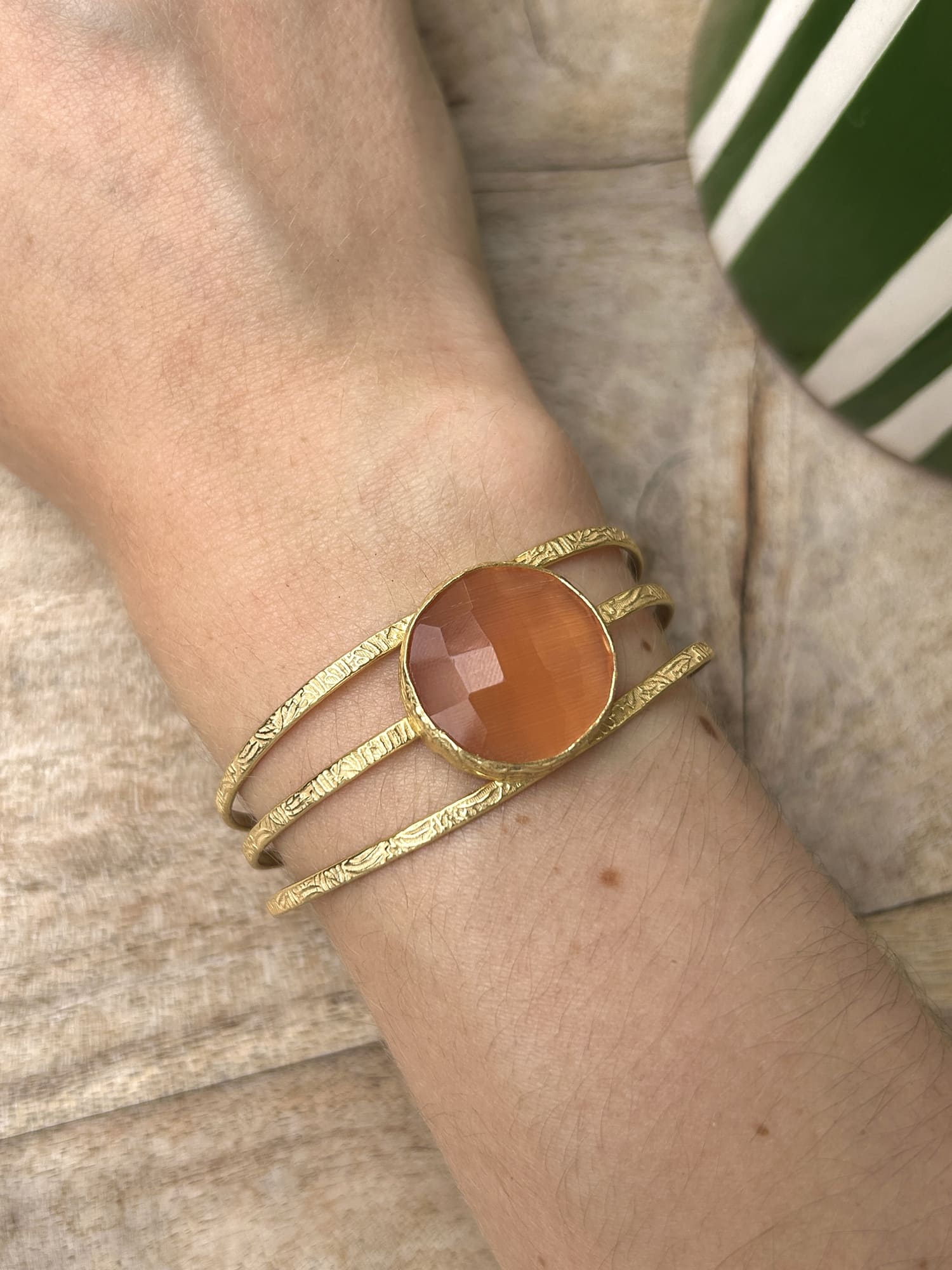 Bracelet manchette en laiton doré et pierre orange au poignet