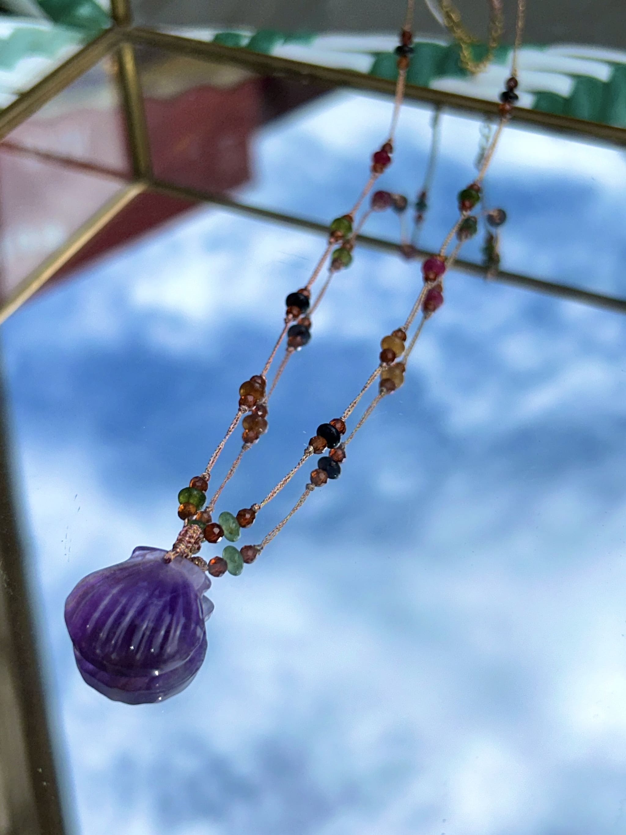 Gros plan du collier mettant en valeur les perles d'agate et le coquillage 