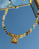 Gros plan sur le collier Daisy Square – détail du pendentif carré doré 