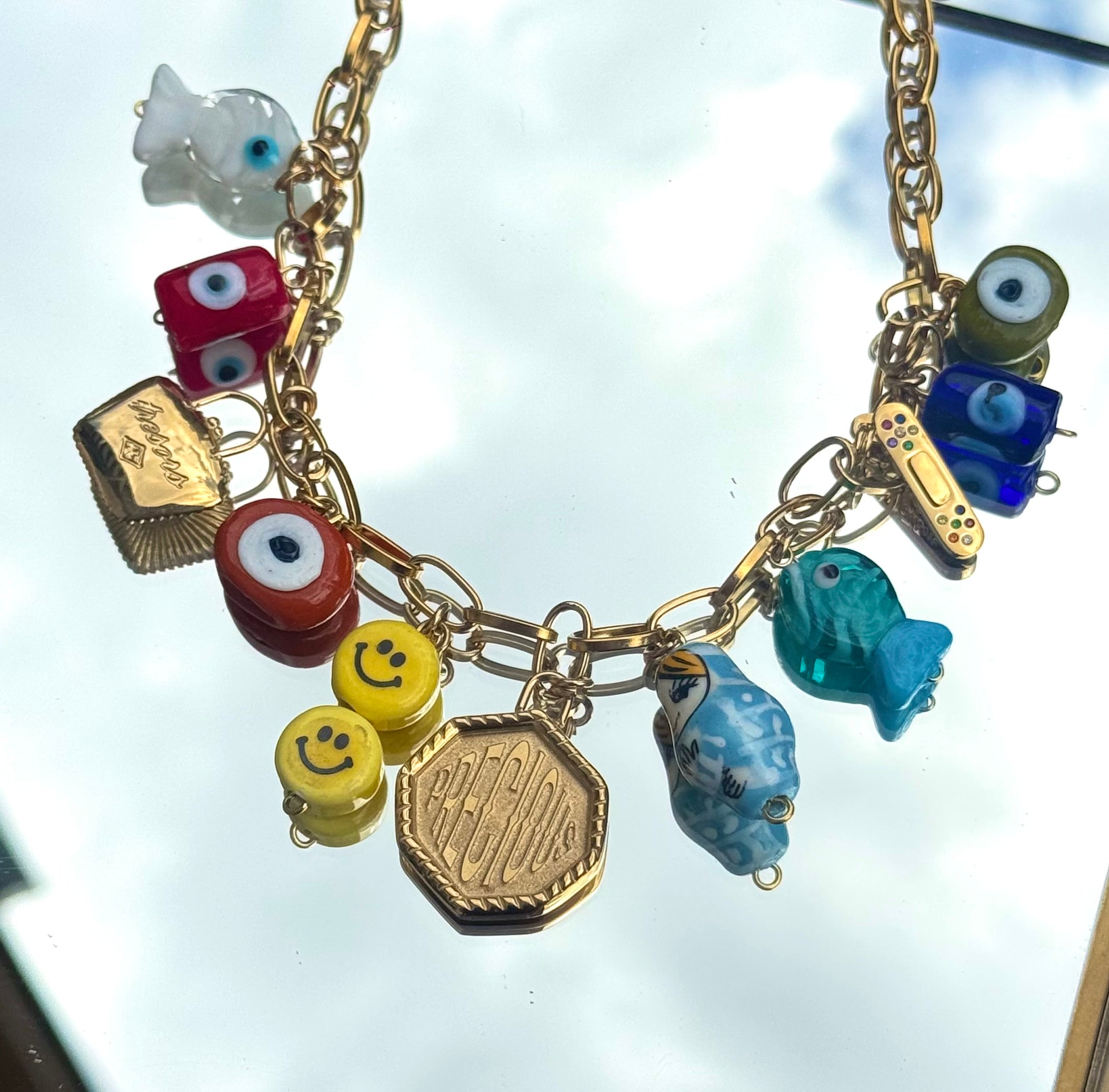 Gros plan du collier Kchoush avec 11 charms dorés symbolisant chance, guérison et prospérité