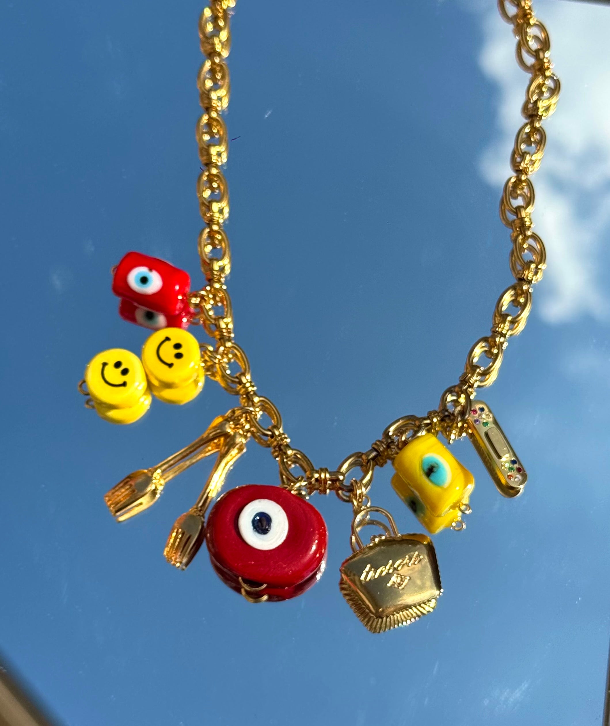 Gros plan du collier Kchoush avec 7 charms dorés symbolisant chance, guérison et prospérité