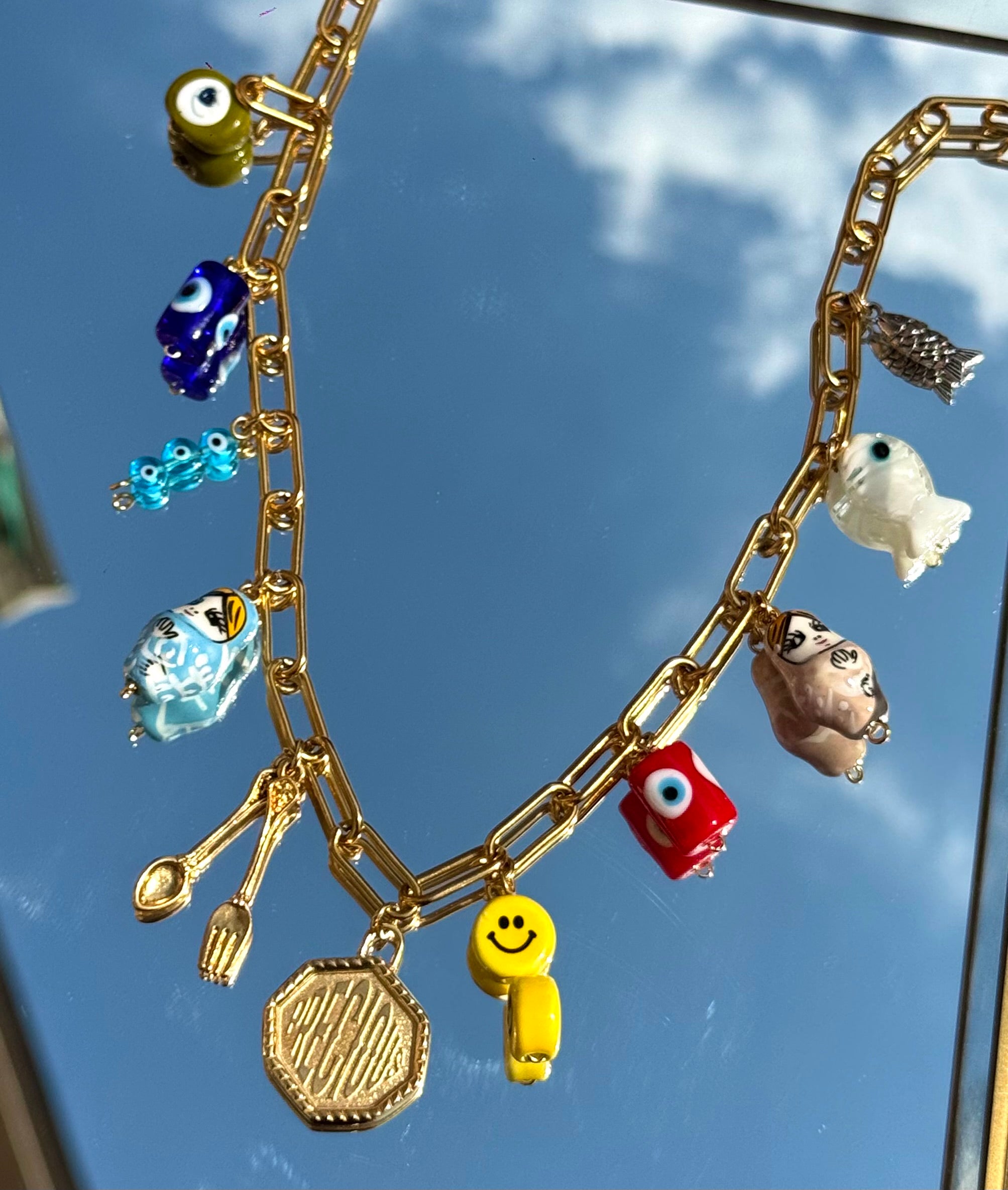 Gros plan sur les 11 charms du collier Mamie Esther – symboles de prospérité et poisson précieux