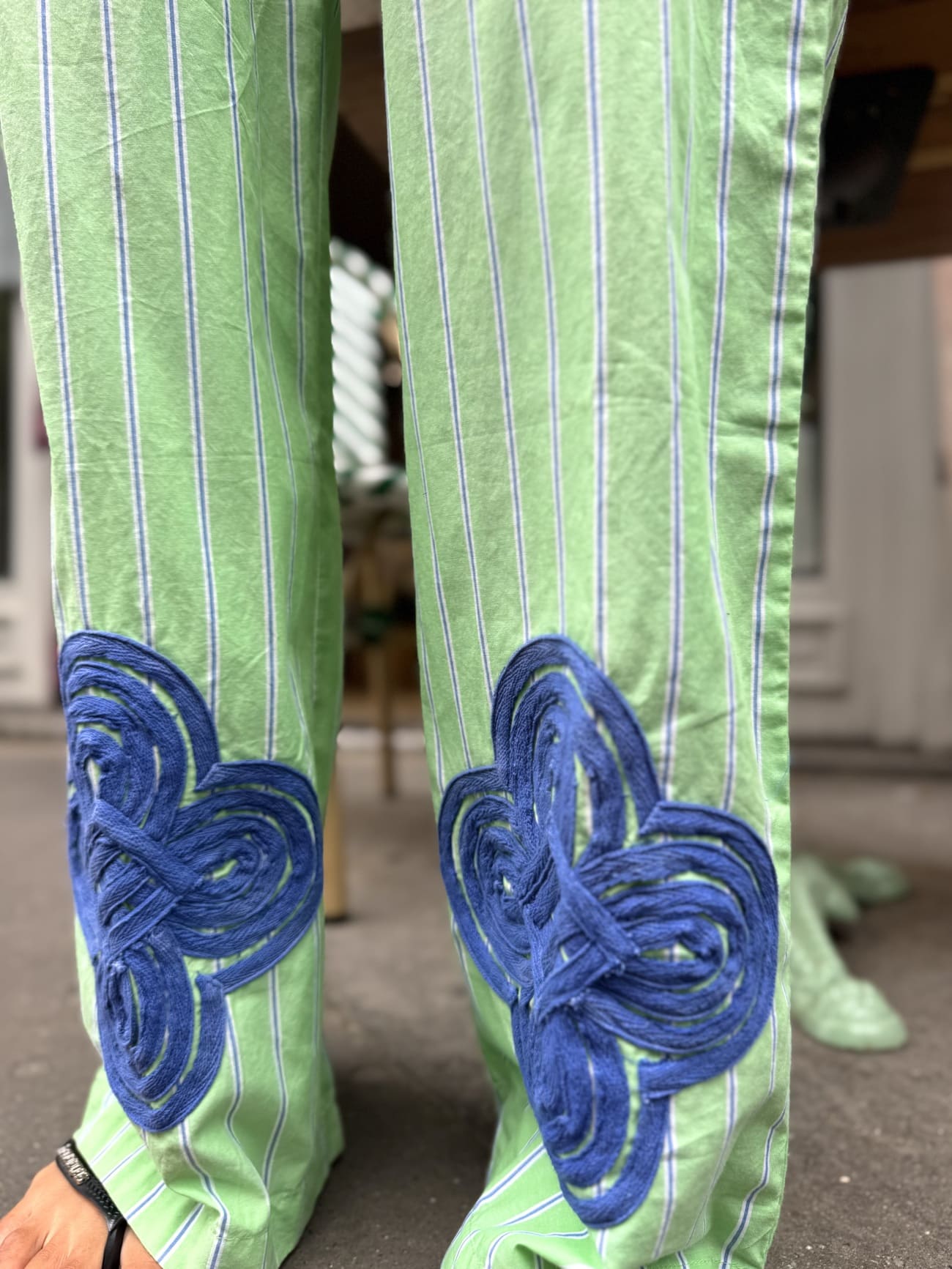 Détail broderie bleue sur pantalon rayé vert