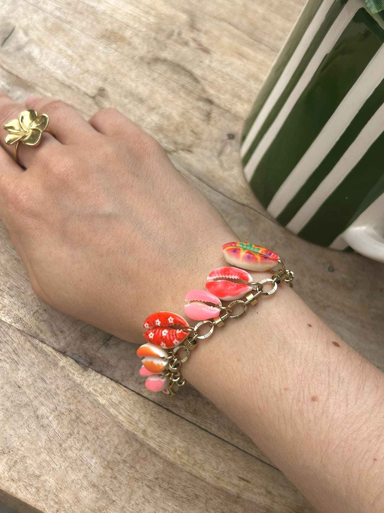 Bracelet à breloque coquillage dorée porté au poignet d’une femme