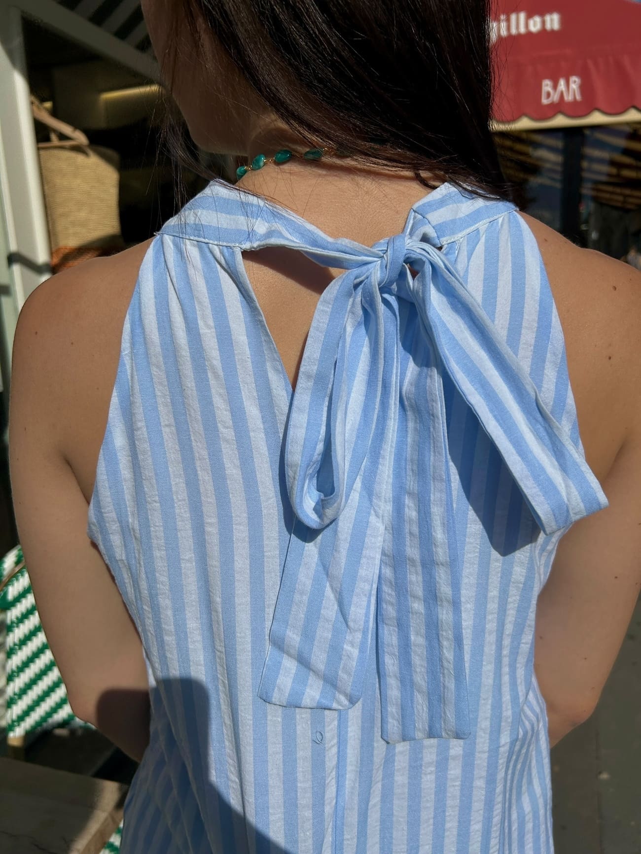 Gros plan sur le nœud dans le dos de la robe longue rayée bleu ciel