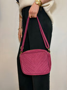 Détail des surpiqûres sur un sac en daim fuchsia