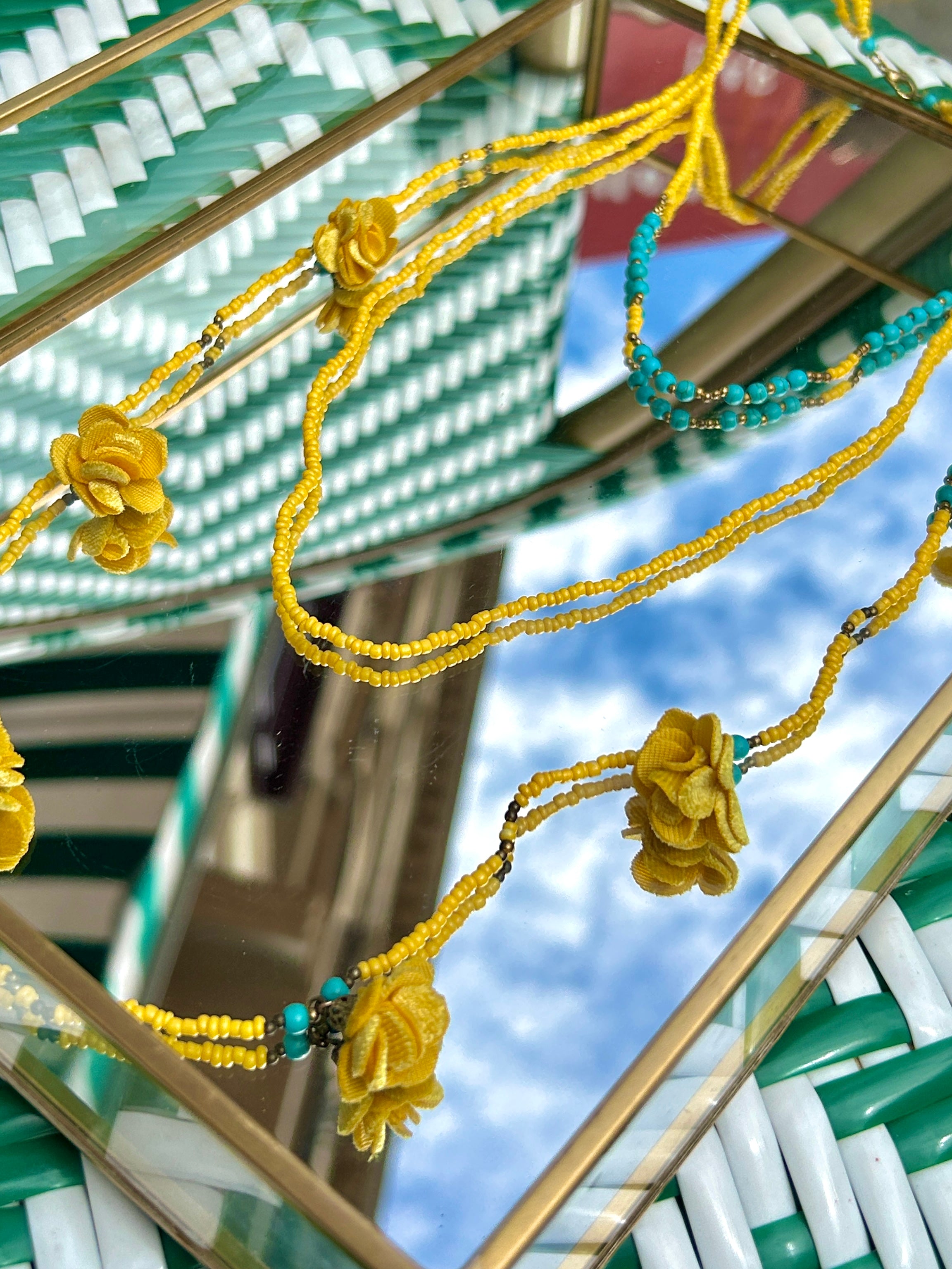 Sautoir en perles rocailles jaune et bleu turquoise posé 