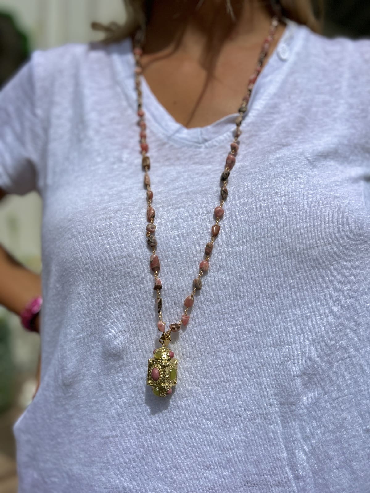 Femme portant le sautoir talisman orné de perles roses, style élégant et féminin