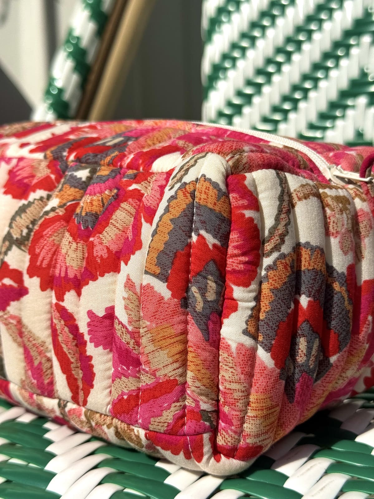 Gros plan sur la finition matelassée de la trousse fleurs rouges