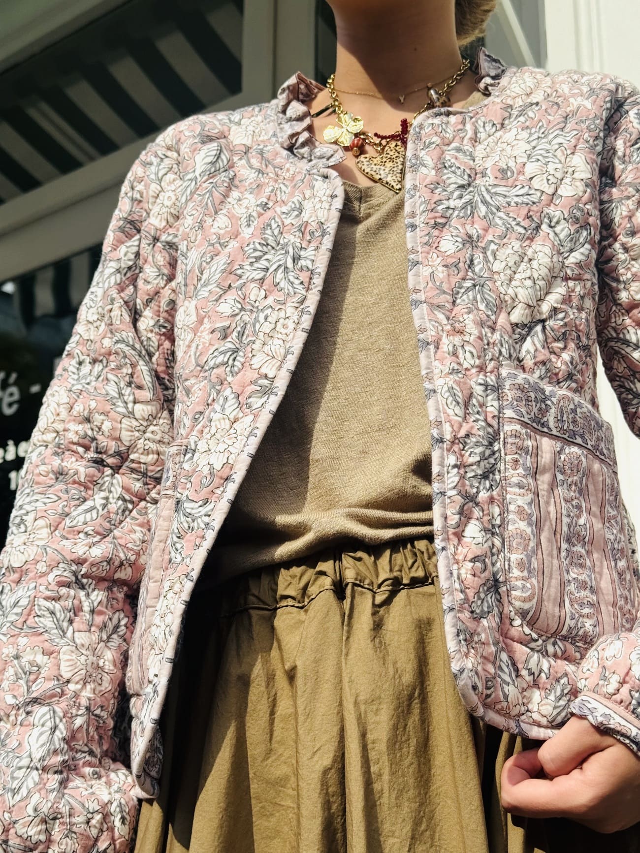 Plan légèrement contre-plongé sur la veste matelassée en coton rose et beige pour femme