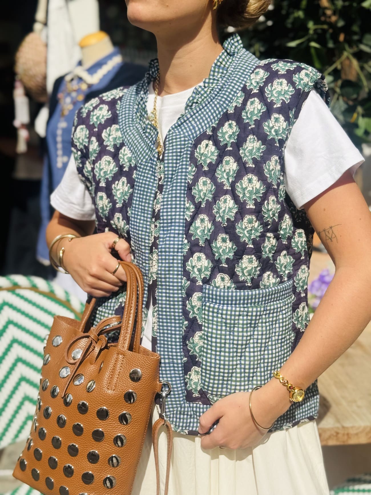 Femme portant la veste matelassée sans manche noir et verte avec un sac en cuir